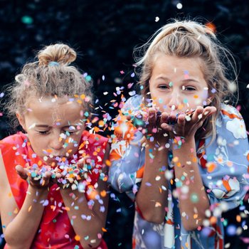 Young girls having fun celebrating while blowing confetti at par